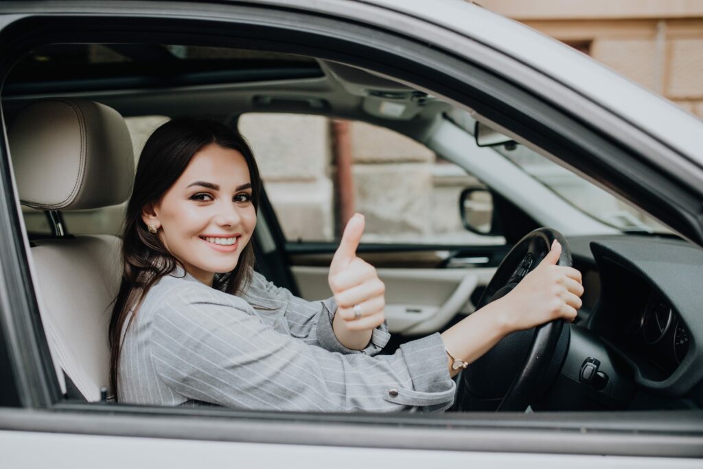 beautiful young latin woman driving her brand new car showing her thumb up 1 scaled